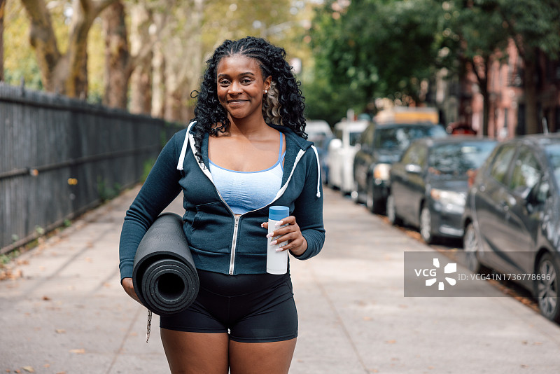 携带瑜伽垫去参加运动训练课程的女人图片素材