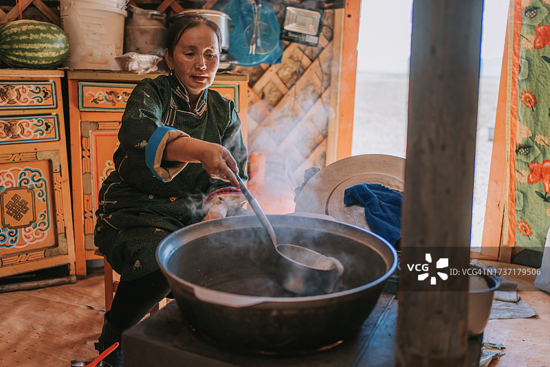 蒙古族游牧妇女在蒙古包内为客人准备传统奶茶图片素材