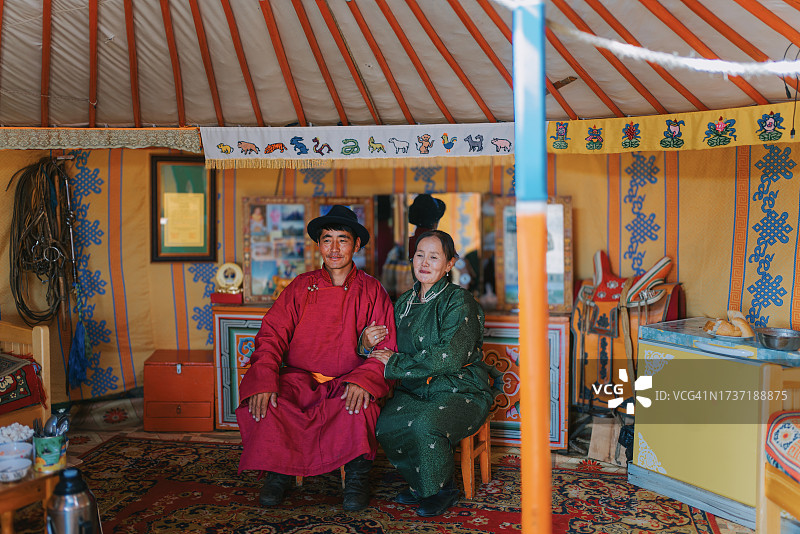 穿着传统服装坐在蒙古包里的蒙古游牧夫妇肖像图片素材