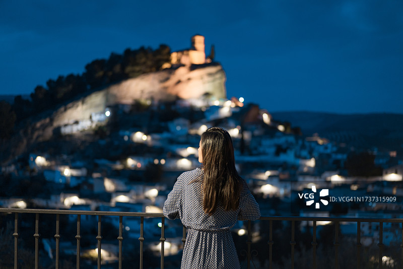 旅行中的女子：身穿蓝色连衣裙的亚洲女子在西班牙格拉纳达的蒙特弗里奥古城夜景图片素材