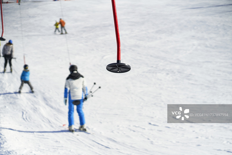 滑雪场滑雪缆车金属臂（前景），背景有人，正面视角图片素材