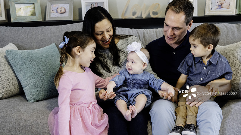 在客厅里休闲合影的快乐可爱年轻多元种族家庭图片素材