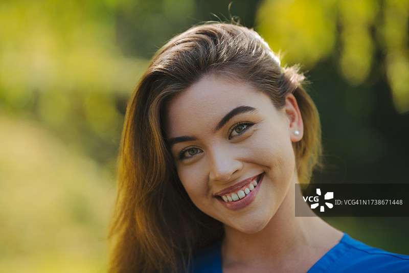 秀发浓密健康，笑容甜美的年轻美女肖像。户外美女肖像，留有文案空间图片素材
