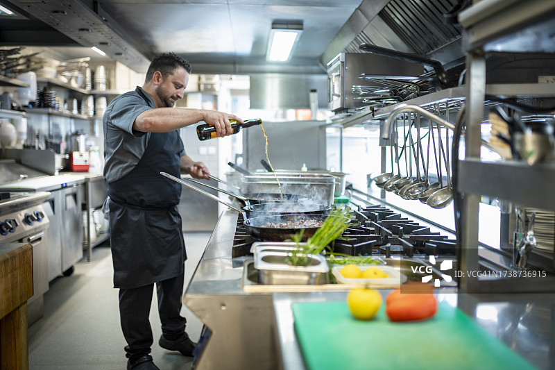 厨师在餐厅厨房的燃气灶上烹饪图片素材
