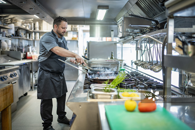 厨师在餐厅厨房的燃气灶上烹饪图片素材