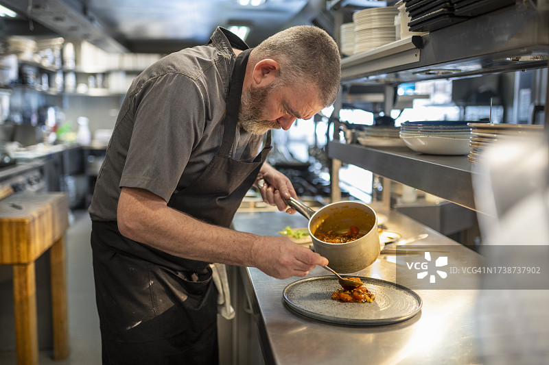 现代餐厅厨房中，厨师摆盘鳕鱼菜肴“圣尤斯塔基奥鳕鱼”图片素材