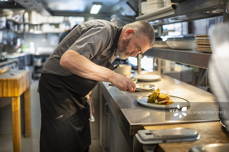 现代餐厅厨房中，厨师摆盘鳕鱼菜肴“圣尤斯塔基奥鳕鱼”图片素材