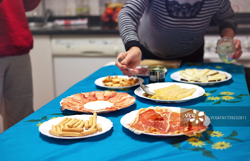 年长的女人正在准备家庭餐桌。图片素材