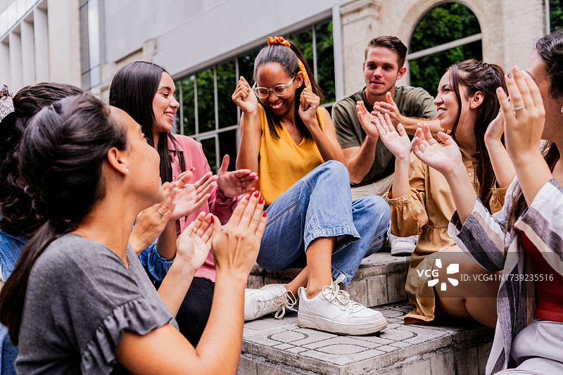 户外，朋友们拍手祝贺年轻女人图片素材
