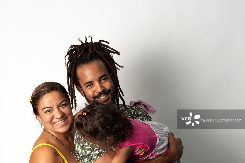 在白色背景下拍摄的多民族幸福家庭的美丽肖像，加勒比父亲和墨西哥母亲拥抱女儿图片素材