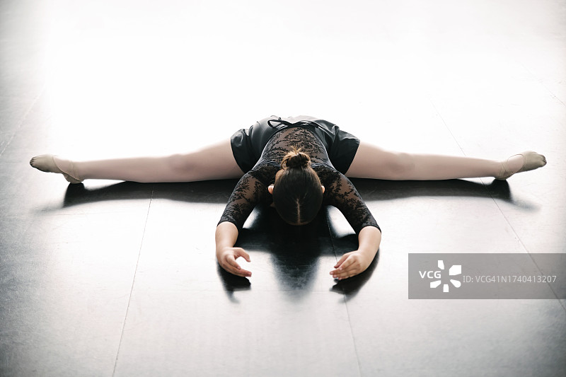 年轻芭蕾舞演员在地板上做劈叉图片素材
