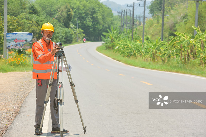 站在泰国道路中间使用经纬仪的测量员图片素材