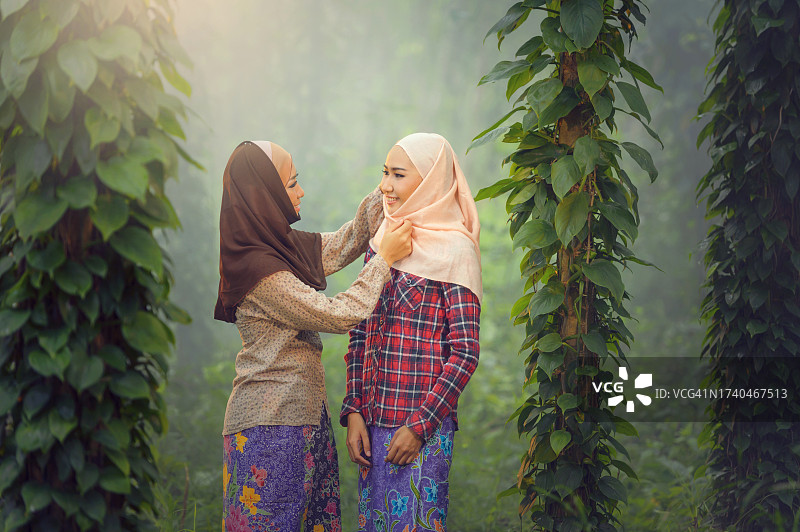 在森林里调整朋友头巾的微笑女人图片素材