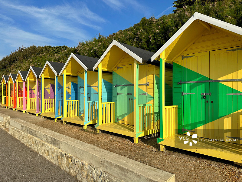 英国肯特郡福克斯通海滩上一排彩色木制海滩小屋图片素材