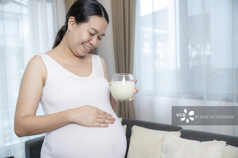 亚裔孕妇在家喝鲜牛奶，心情愉悦图片素材