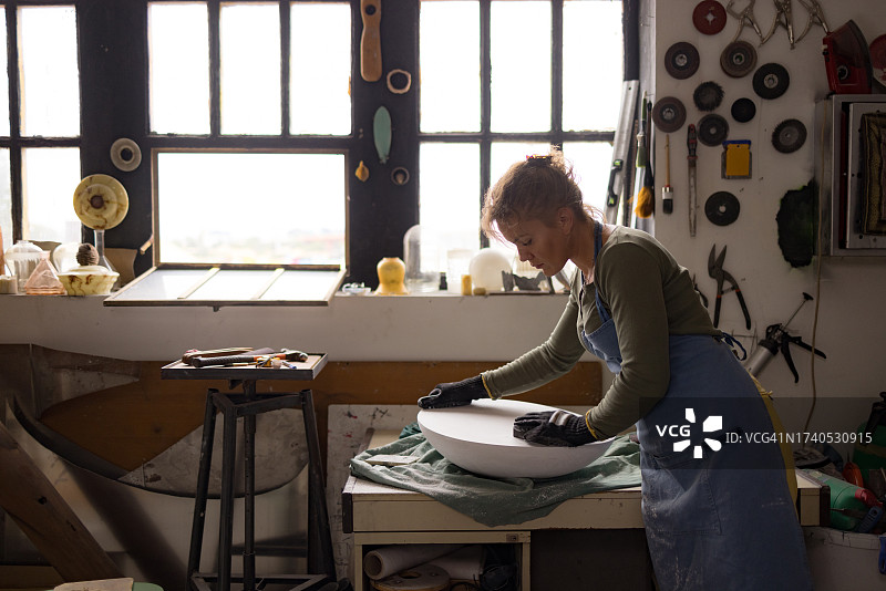 女艺术家在工作室用砂纸打磨雕塑图片素材