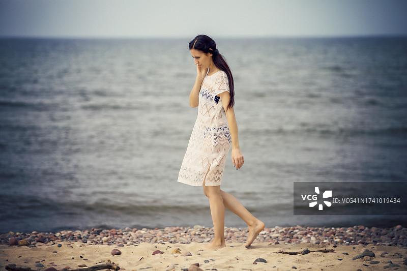 在沙滩上散步的年轻女人图片素材