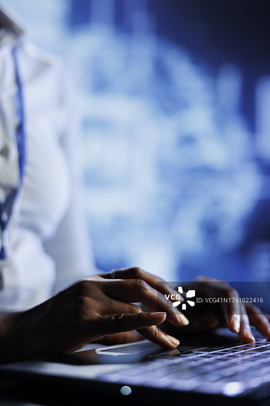 女子在桌旁使用笔记本电脑的腰部特写图片素材