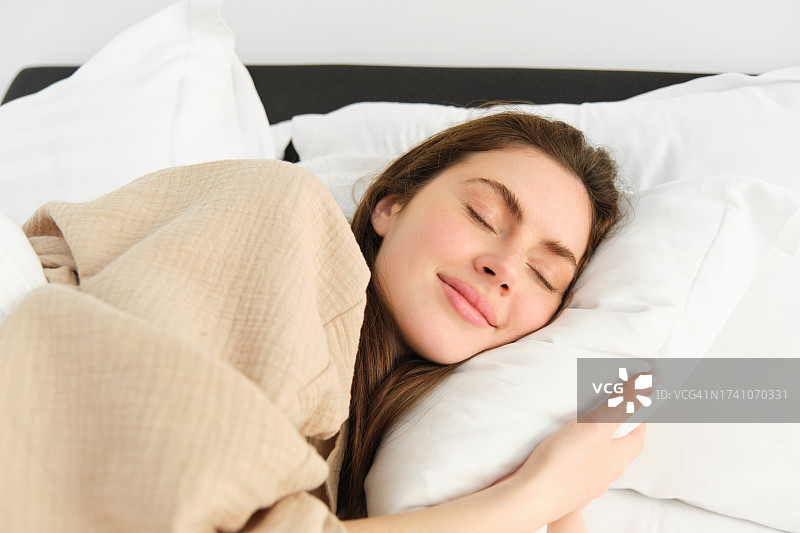 年轻女子在家里的床上睡觉图片素材