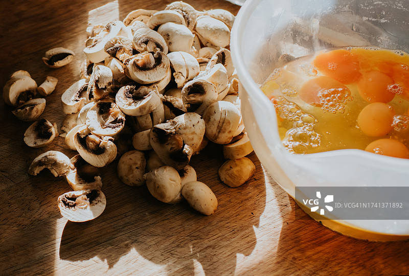 砧板上的生蘑菇和装满鸡蛋的搅拌碗特写图片素材