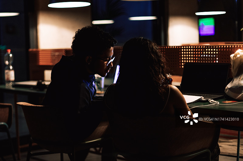 在图书馆使用无线网络的男女合影：使用笔记本电脑工作图片素材