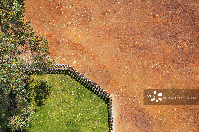 农舍庭院绿草与红色沙漠的对比图片素材