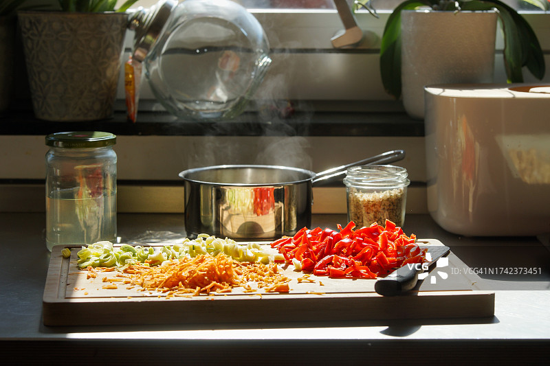 阳光厨房餐桌上用刀和锅切割彩色蔬菜图片素材