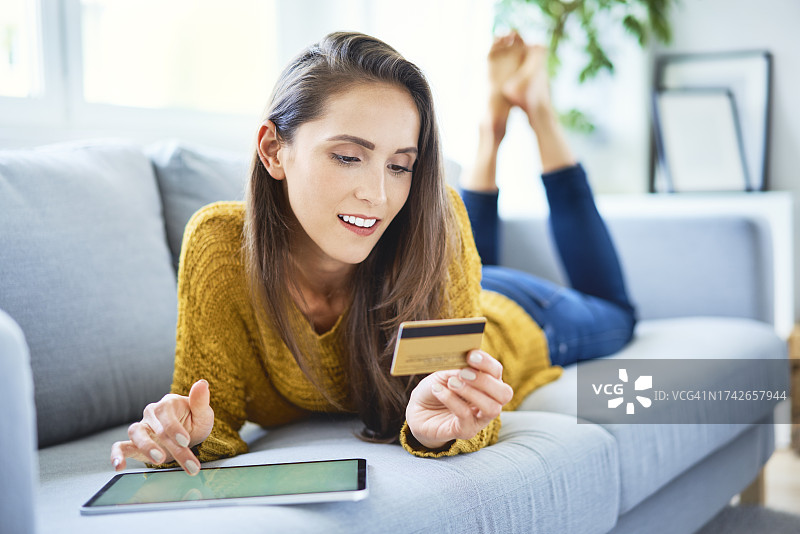 使用平板电脑和信用卡在线购物的迷人微笑女人图片素材