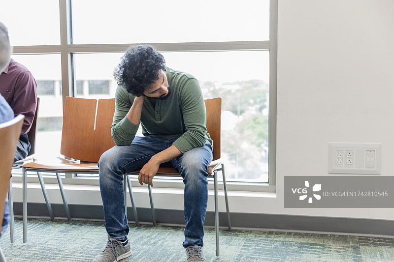 疲惫的年轻男人坐在社区中心的候车室里图片素材