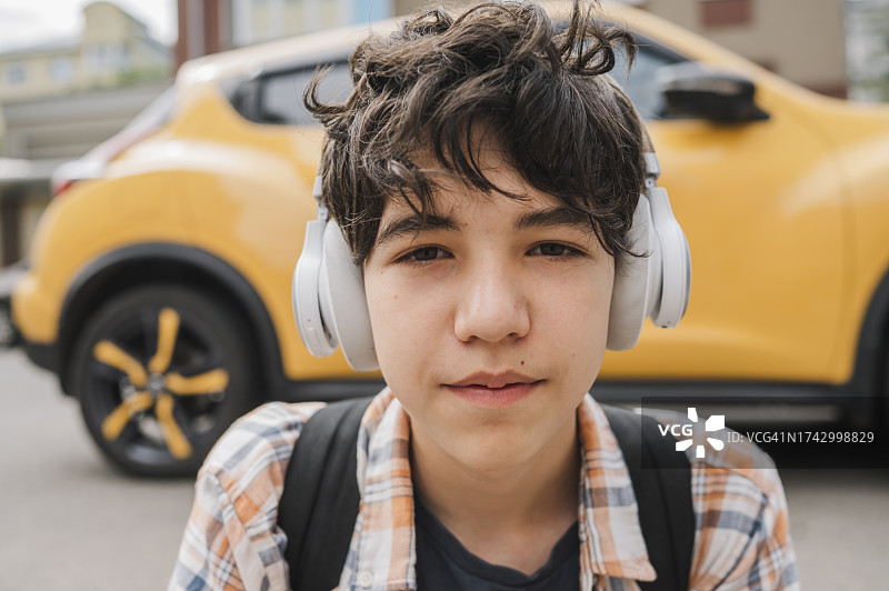 青少年男孩戴着耳机在路上听音乐图片素材