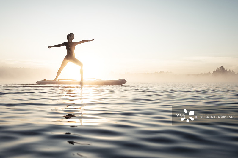 清晨在德国巴伐利亚州基尔希湖上练习桨板瑜伽的女人图片素材