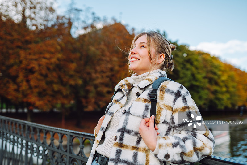 公园桥上的休闲：背着背包的女士在西欧的秋天享受宁静的休息图片素材