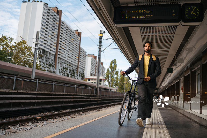 时尚男人在铁路站台上推着自行车图片素材