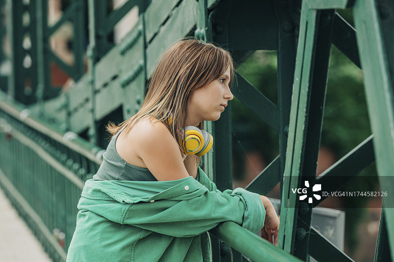 戴着无线耳机靠在栏杆上的女孩图片素材