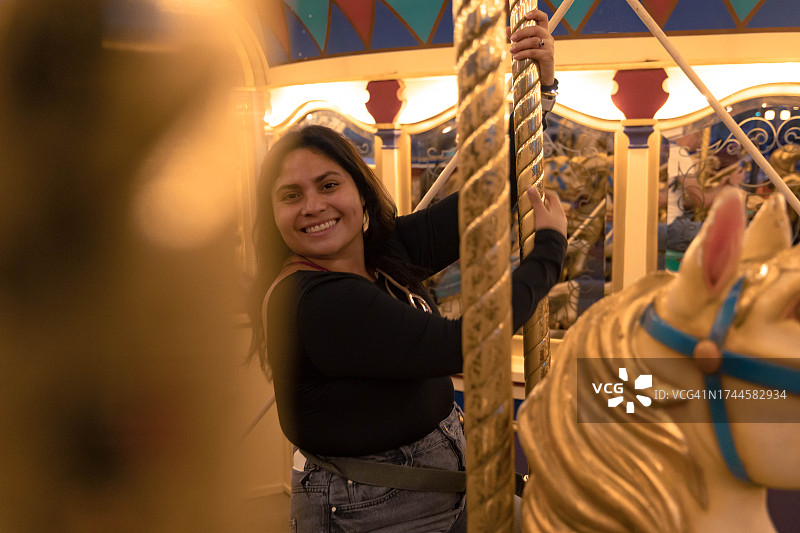 快乐的成年女人在巴黎夜晚的旋转木马上图片素材