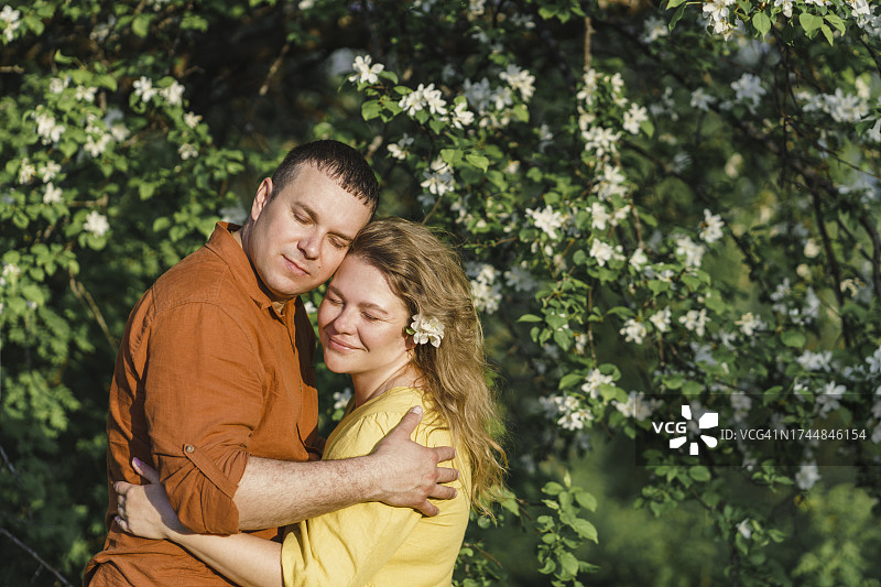 幸福情侣在盛开的树前拥抱图片素材
