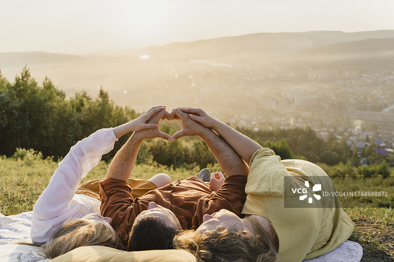 父母和女儿在日落时比心图片素材