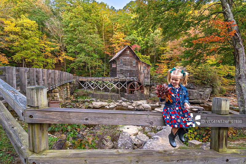 秋季，美国西弗吉尼亚州，在阿巴拉契亚山脉的巴布科克州立公园，年轻女孩探索格莱德溪磨坊。图片素材