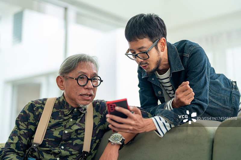 多代连接：亚洲自由职业者和年迈的父亲在家分享数字瞬间图片素材