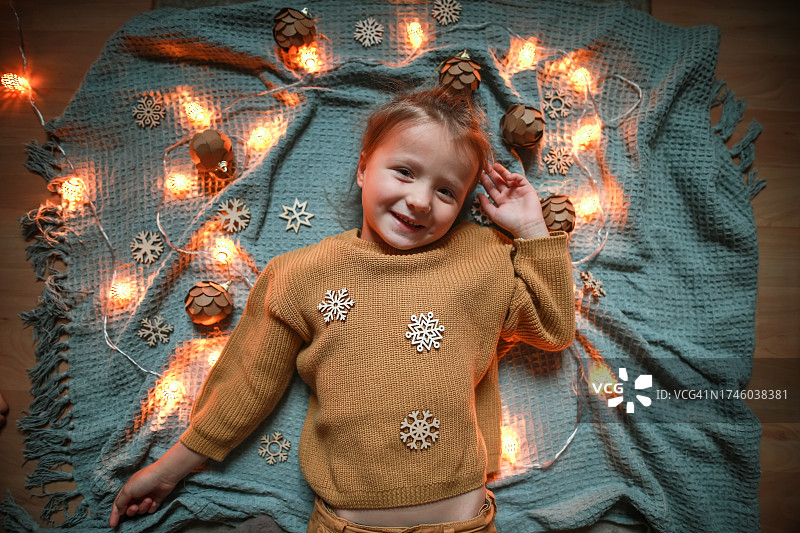 圣诞温馨：女孩与木制雪花和圣诞花环的俯视图片素材