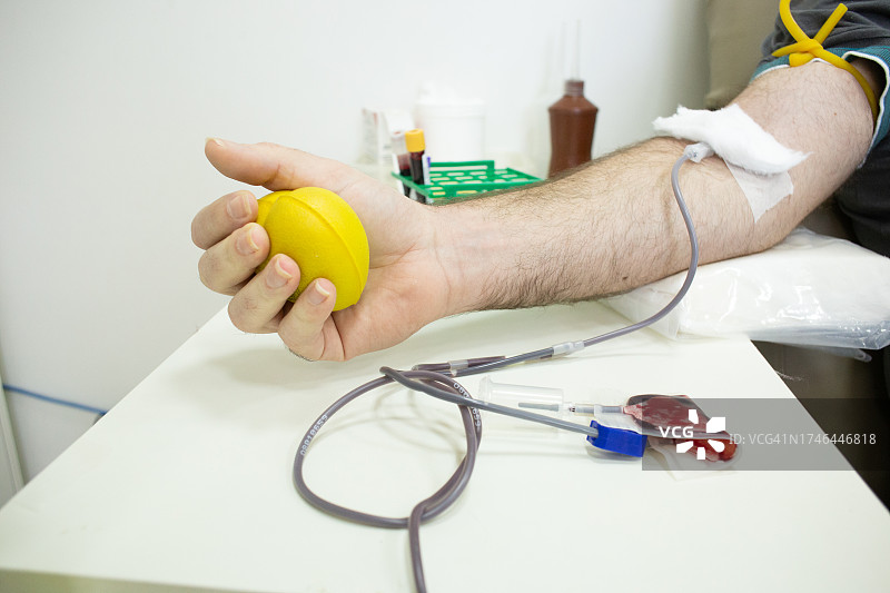 白人献血手臂细节：挤压黄色橡胶球图片素材