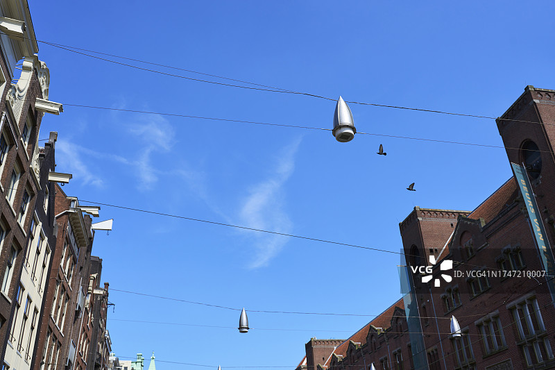 城市街道建筑物外悬挂在绳索上的灯或灯笼的仰视角度图片素材