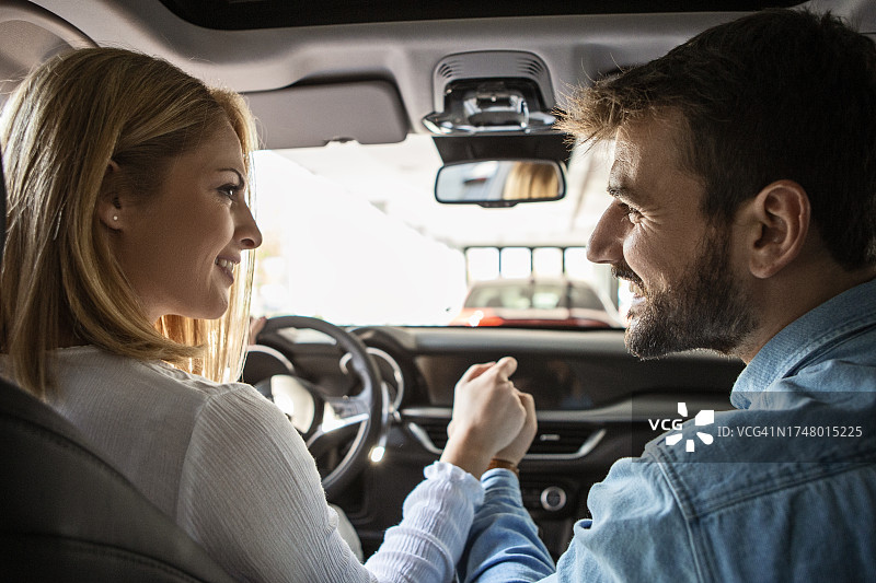 年轻情侣在车里，牵手看车想购买图片素材