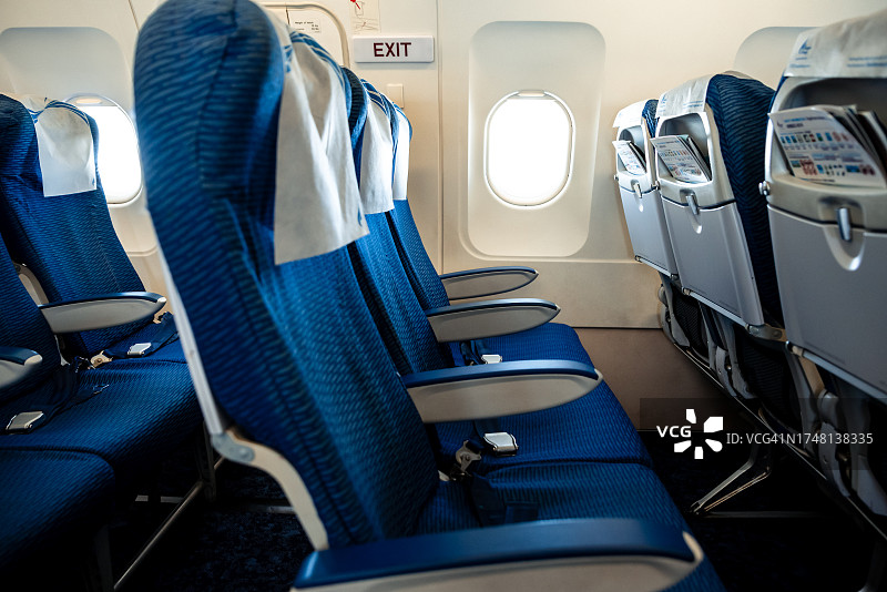 飞机内一排三个蓝色座椅和一扇窗户图片素材