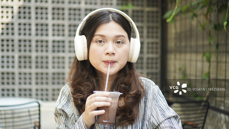 戴着耳机听音乐，喝冰巧克力图片素材