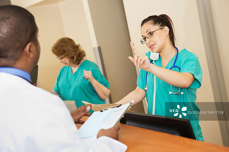忙碌的护士在护士站和医生交谈图片素材