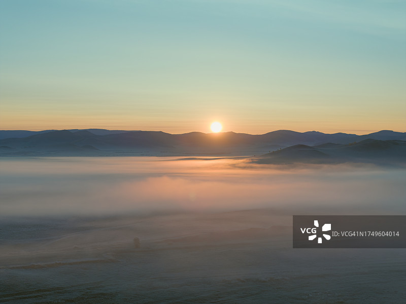 日出时笼罩在雾中的秋季草原图片素材