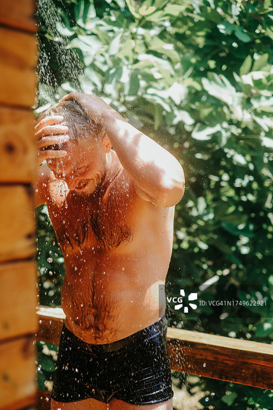 金发男子在热带气候的夏季阵雨中沐浴图片素材