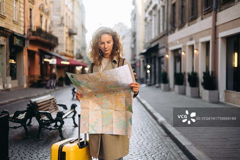 美丽的女人在秋天用旅游地图探索欧洲城市图片素材