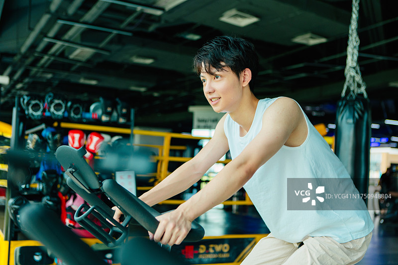 男子在健身房骑动感单车训练——健康的生活方式，身心健康训练，幸福和健康图片素材